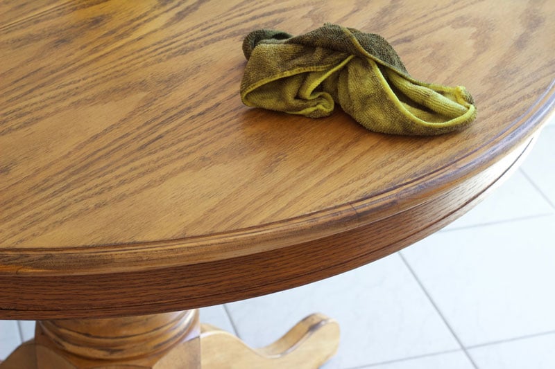 Use a rag to wipe the stain on the dining room table, following the wood grain