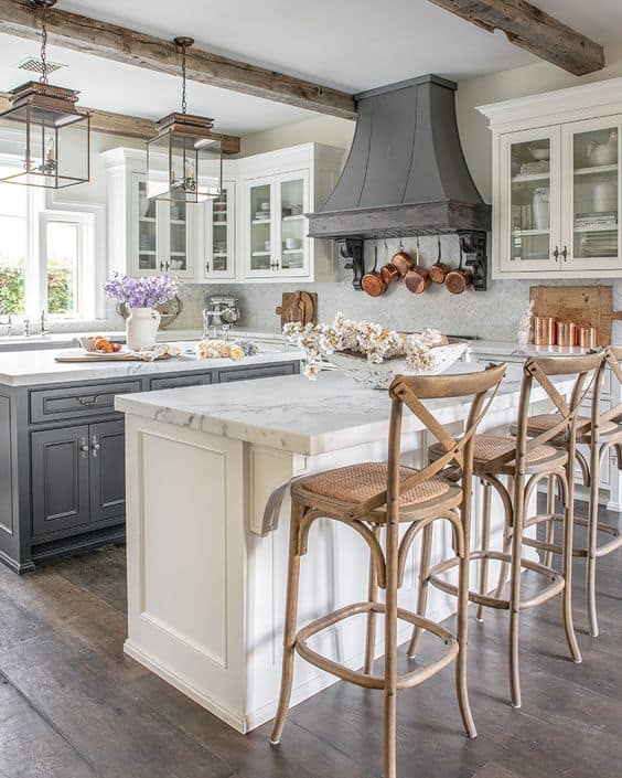 Tips for styling a farmhouse kitchen; wood barstools, dark oven, white cabinets, wood beams