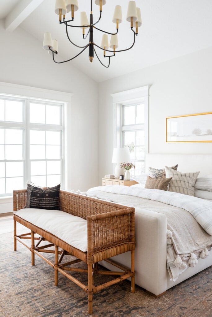 Studio McGee by Bedrooms: Studio McGee House; white walls, neutral colours, vaulted ceiling, large window, grey bed with white linen, wicker seating