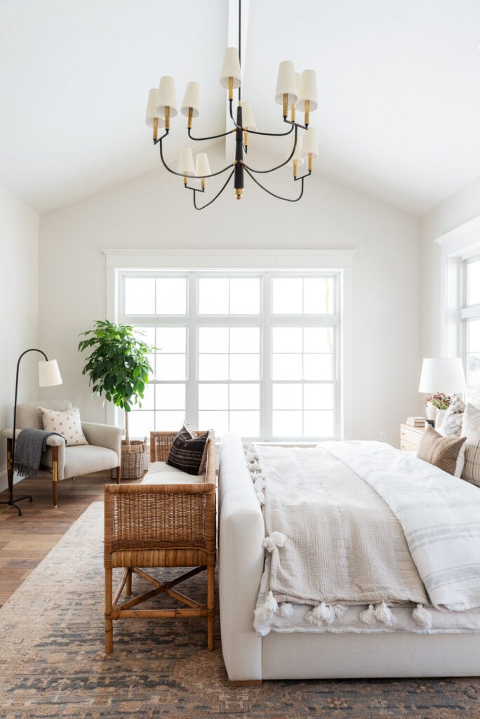 Studio McGee by Bedrooms: Studio McGee House; white walls, neutral colours, vaulted ceiling, large window, grey bed with white linen, wicker seating