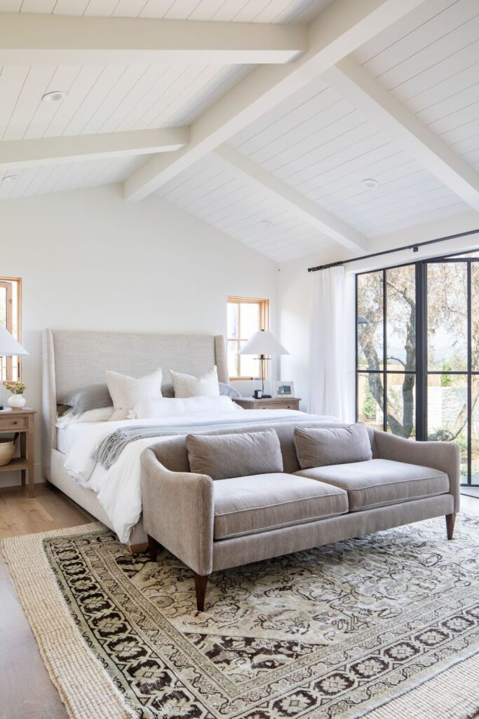 Studio McGee by Bedrooms: The Crestview House; white walls, vaulted ceiling, grey bed with white linen, grey couch 