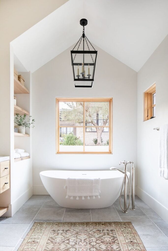 Studio McGee Bathrooms; white bathtub, vaulted ceiling, oak wood, black light