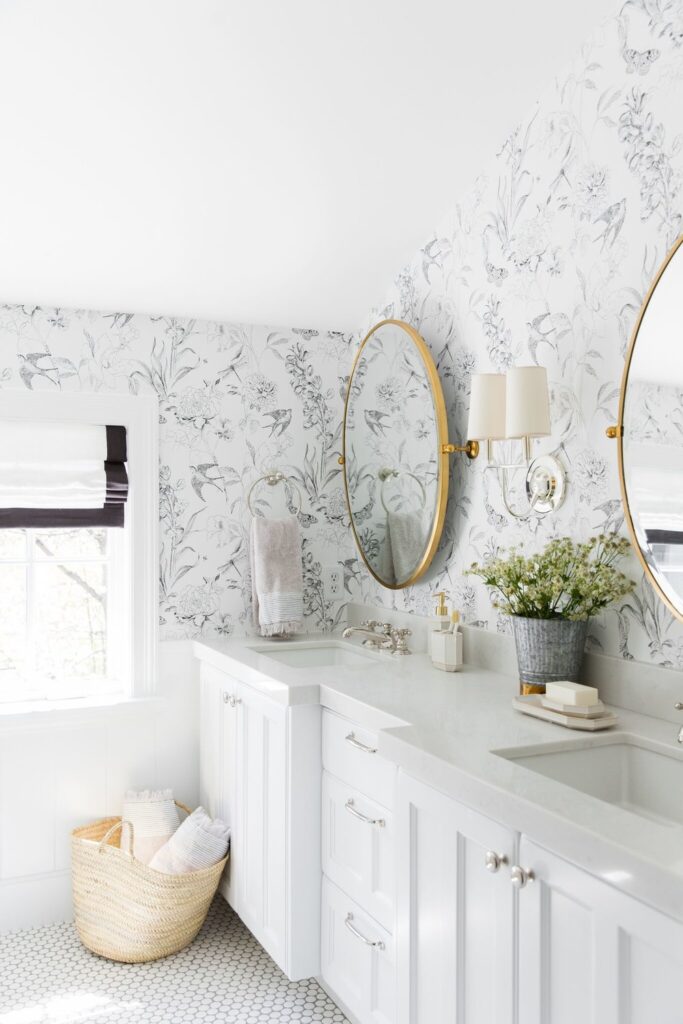 Bathrooms by Studio McGee; marble counter, white vanity, wallpaper in bathroom, gold mirror, slanted ceiling