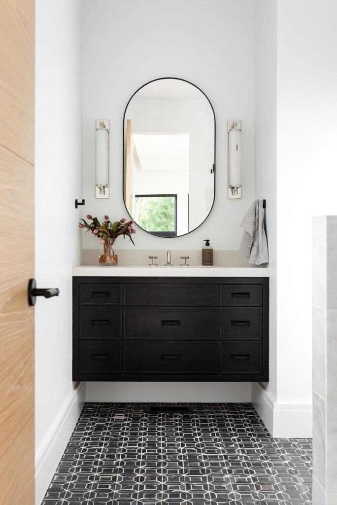 Studio McGee Bathrooms; black vanity, oval mirror, sconces
