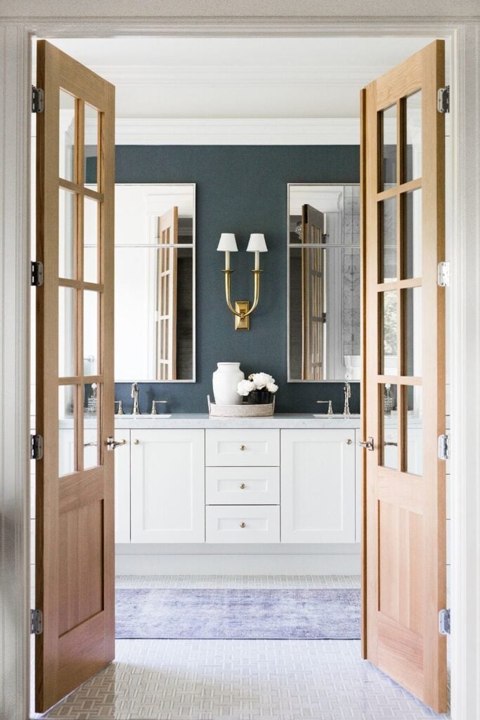 Bathrooms by Studio McGee; dark blue walls, gold accents, white vanity, marble counter tops