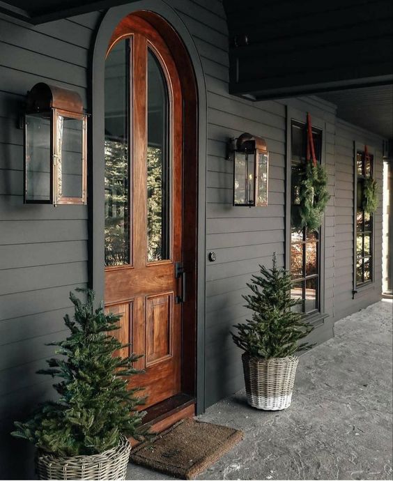 Modern Farmhouse Design Must haves: dark siding, wood door, front porch, large copper scones