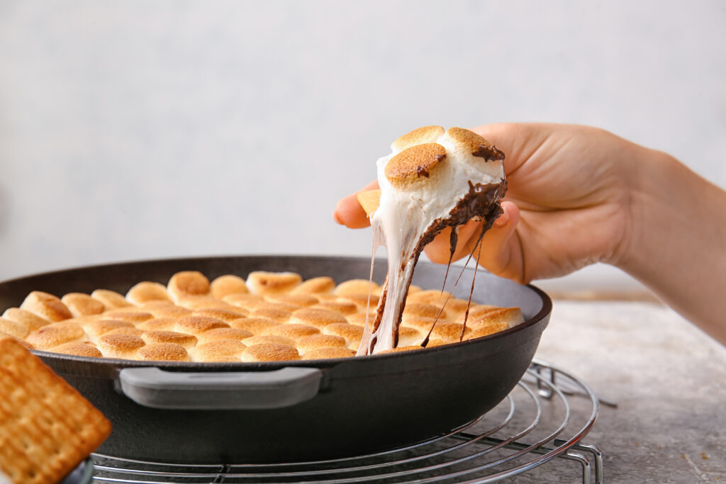 Woman eating delicious S'mores dip at table, closeup -