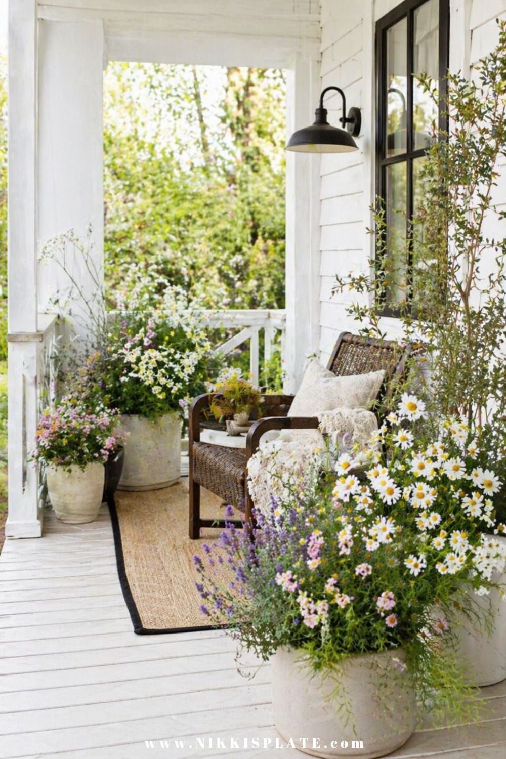 Front porch planter ideas with cottage-style pots filled with daisies, soft flowers, and greenery on a bright porch