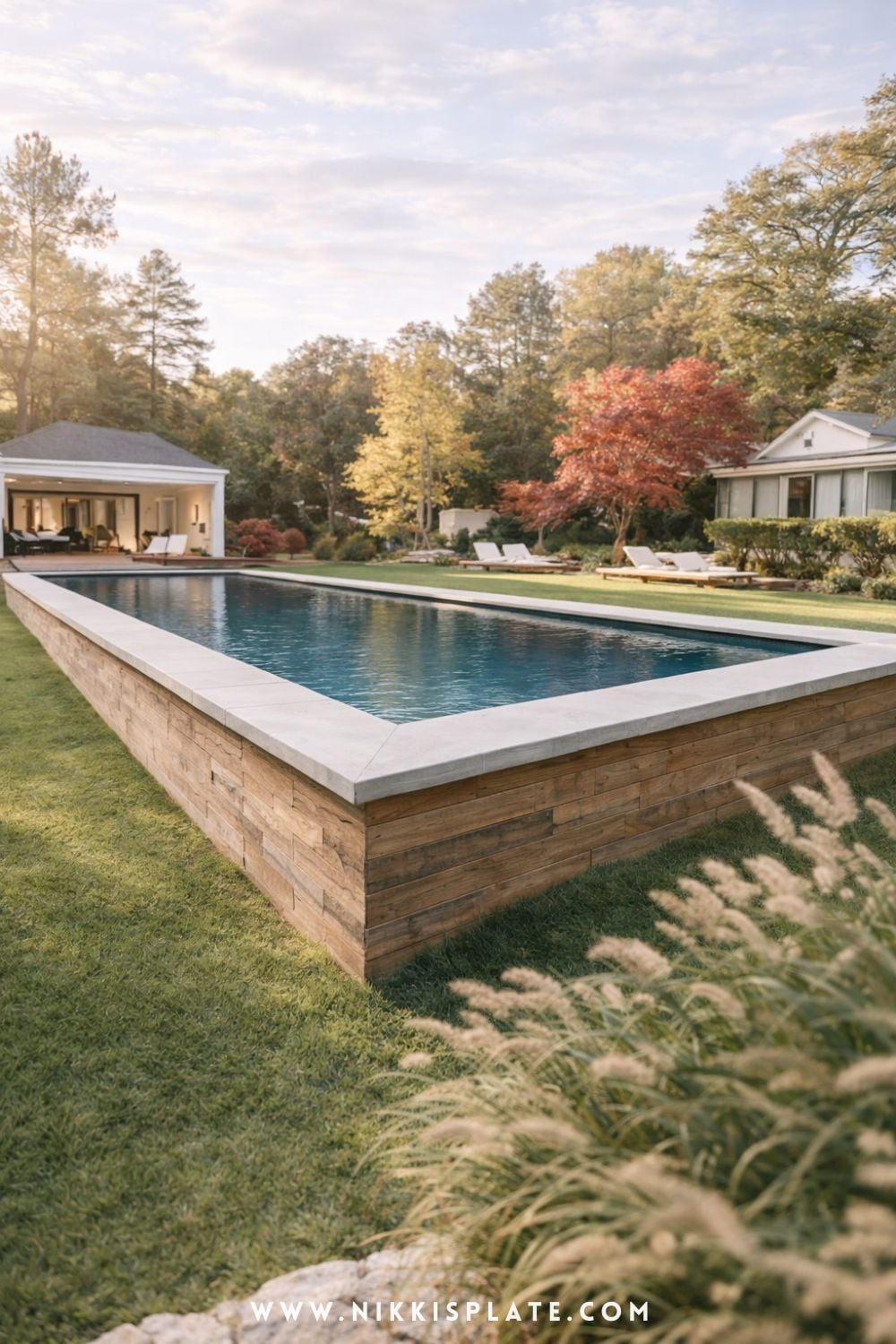 Raised hillside pool with retaining walls featuring wood siding in a modern sloped backyard design