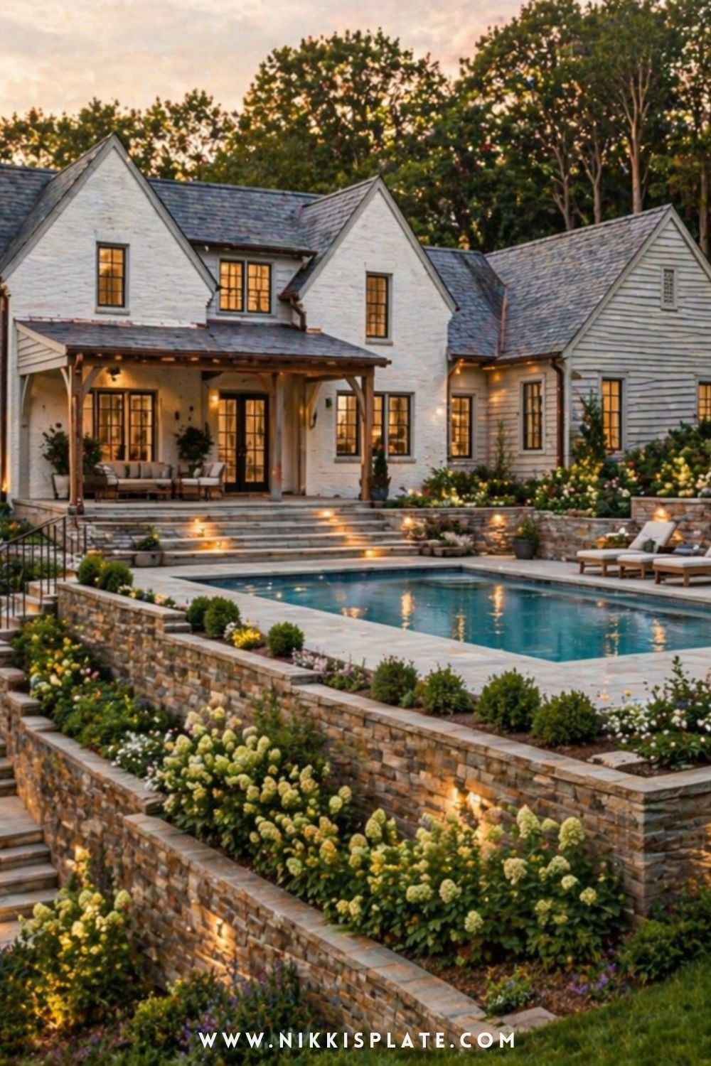 white farmhouse with hillside pool and stone retaining wall creating a tiered backyard with clean landscaping and soft outdoor living space