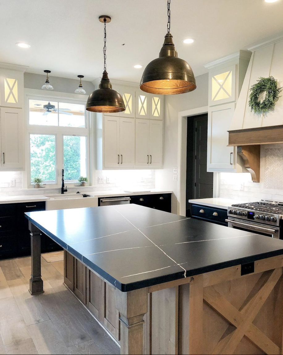 Farmhouse kitchen with black quartz countertops, white and natural wood cabinets
