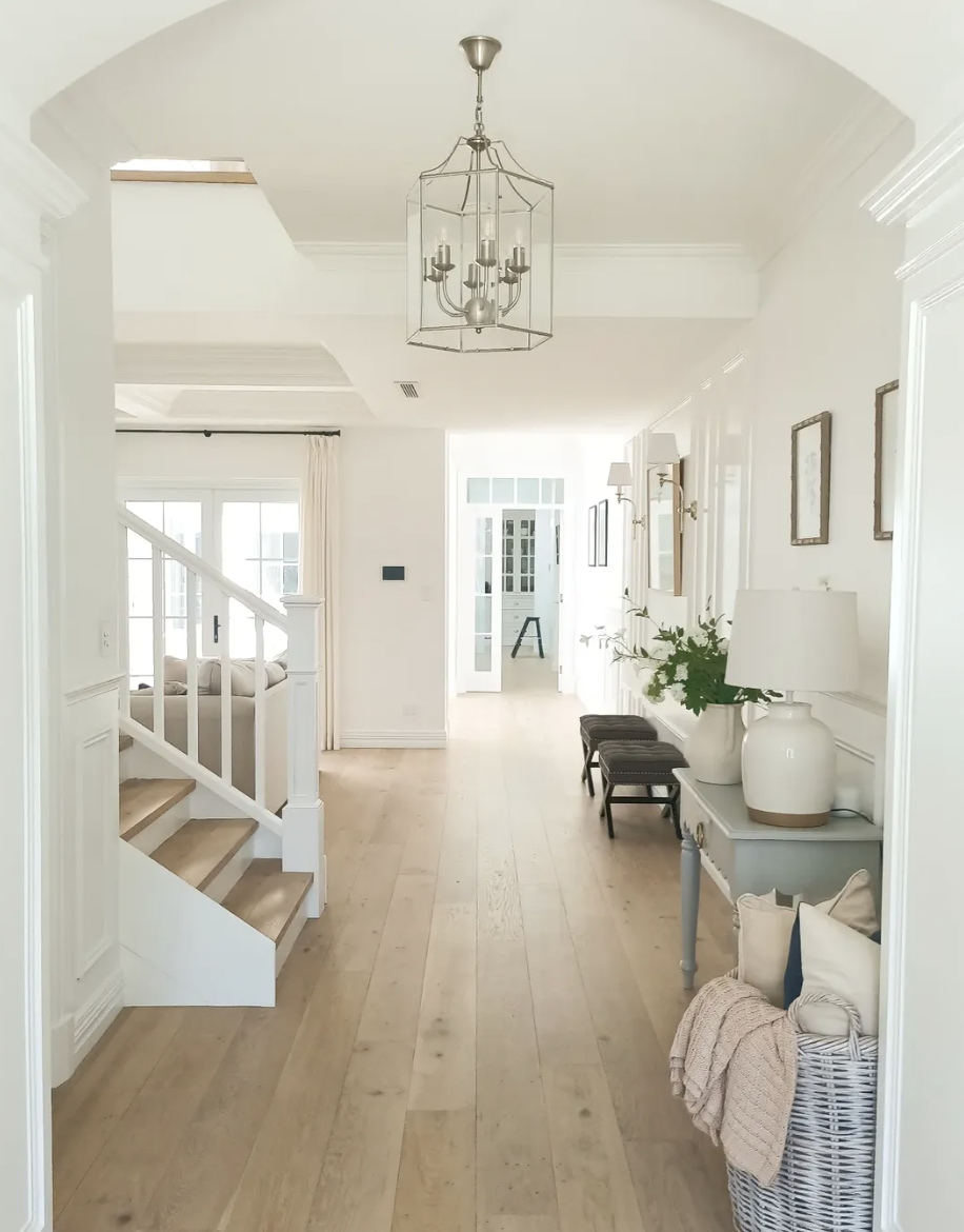 light oak flooring in modern farmhouse entryway with white walls and natural decor