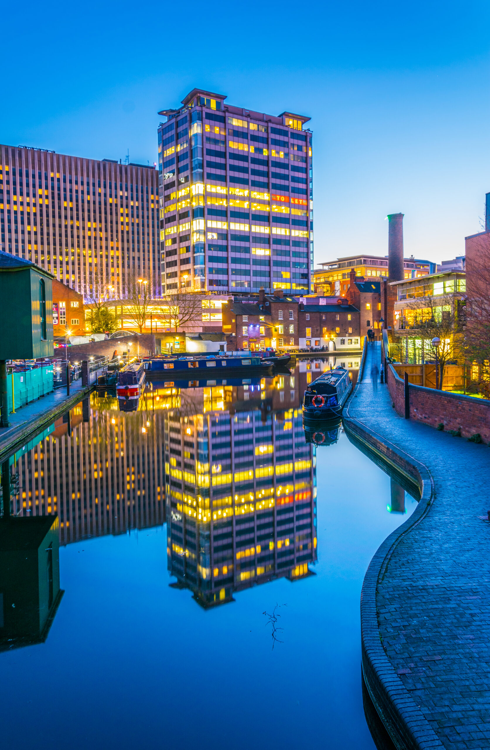 The Best Places To Live in the UK for Expats; Sunset view of brick buildings alongside a water channel in the central Birmingham, England