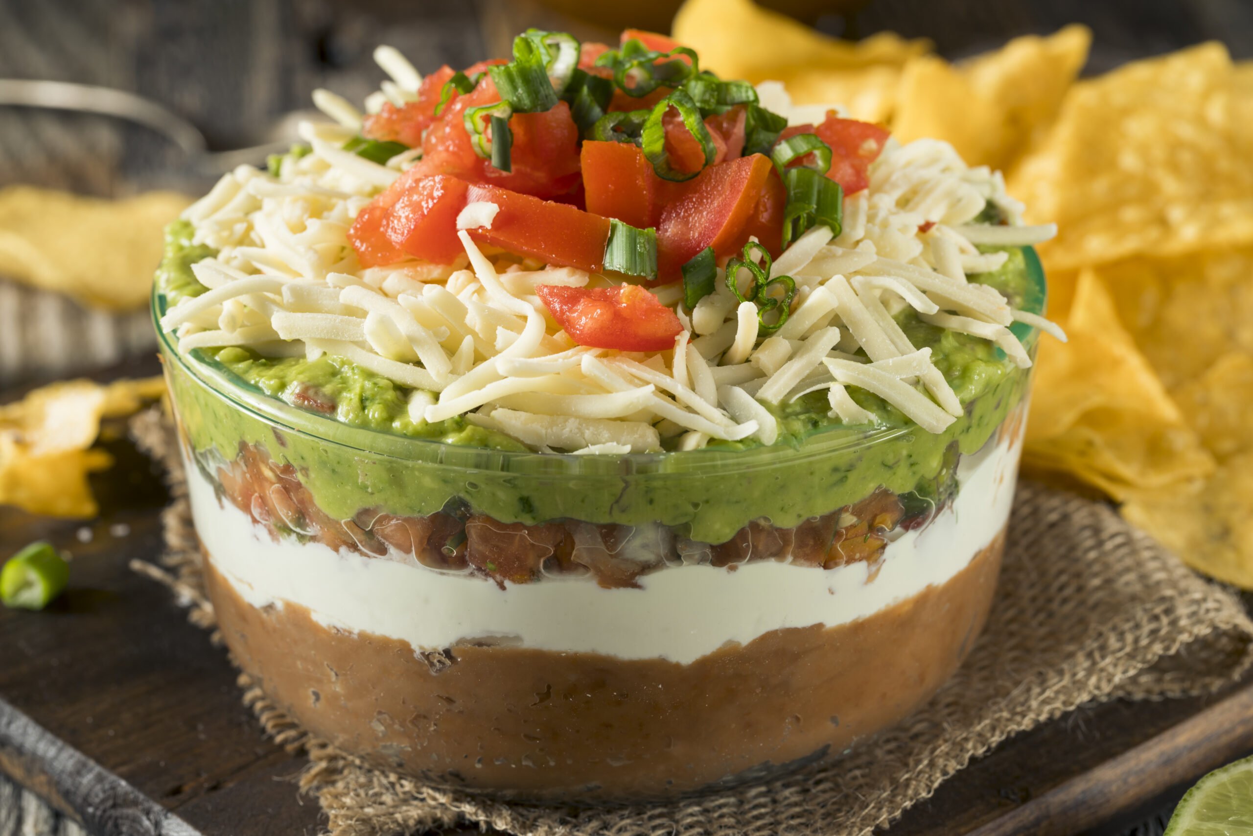 7-Layered Mexican Dip Appetizer; refried beans mixture, sour cream, salsa, guacamole, cheese, tomatoes, and green onions!