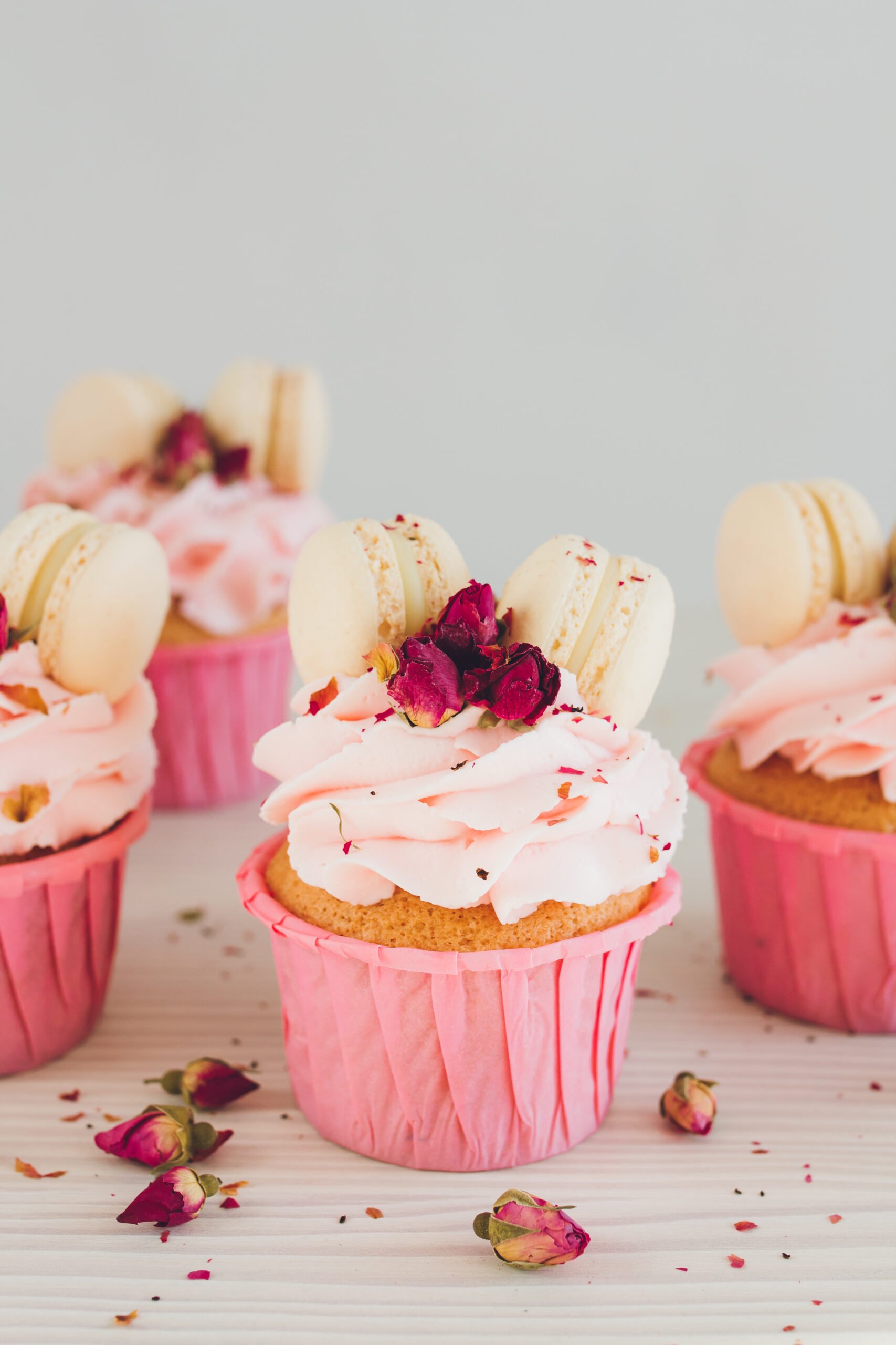 Pink Macaroon Cupcakes; fun pink valentines day cupcakes with edible roses and macaroon cookies! Delicate delicious cupcakes with pink cream, macaroons, and roses for Valentine's day.