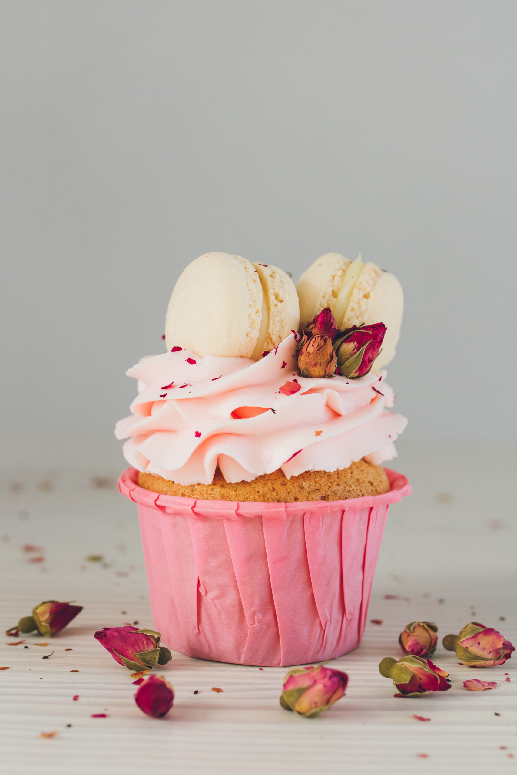 Pink Macaroon Cupcakes; fun pink valentines day cupcakes with edible roses and macaroon cookies! Delicate delicious cupcakes with pink cream, macaroons, and roses for Valentine's day.