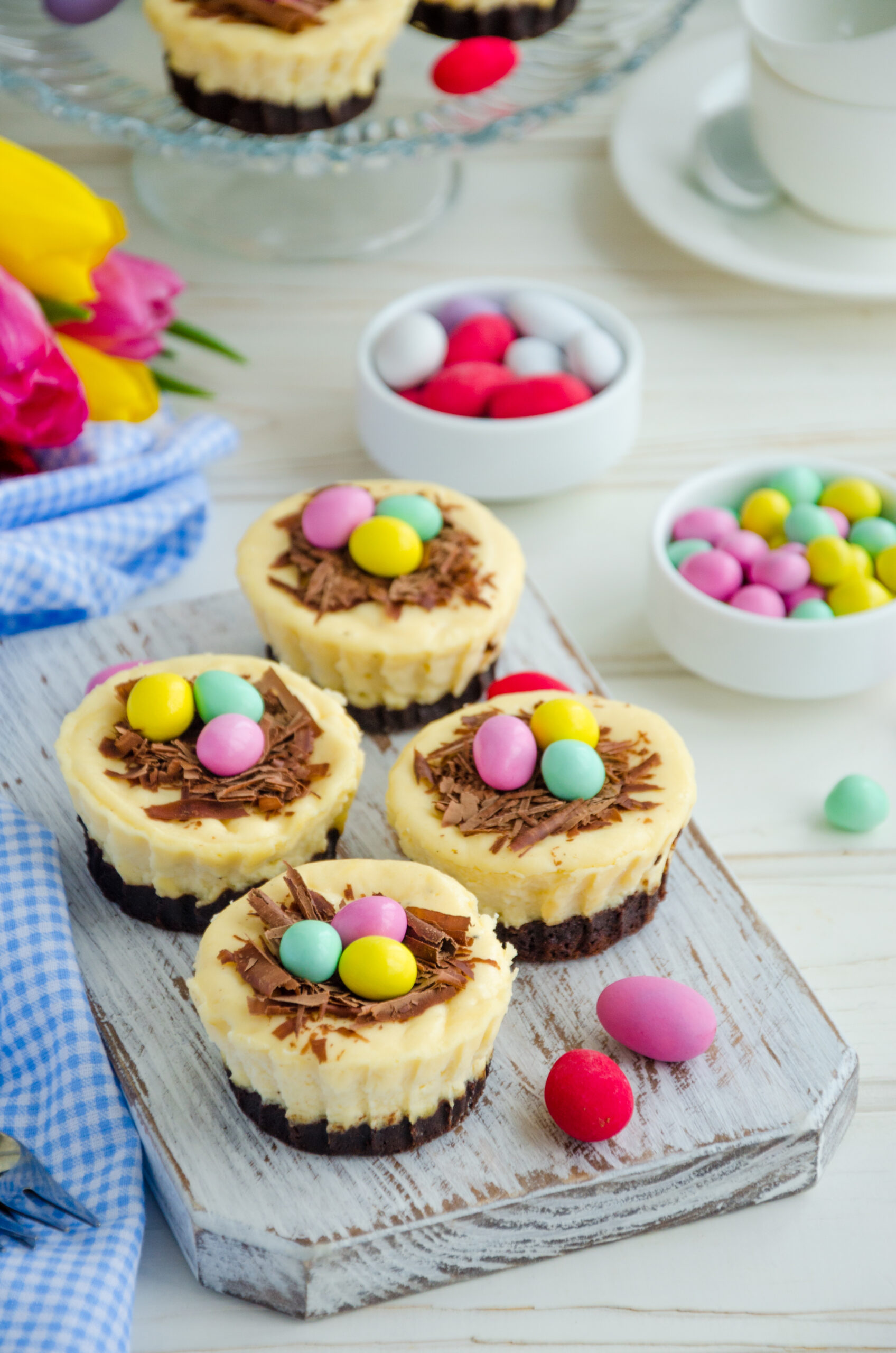 Easter Brownie Cheesecake Birds Nests; brownie crust, creamy cheesecake filling topped with mini eggs for a delicious Easter dessert recipe! Easter mini brownie cheesecake Bird's Nest with chocolate and candy eggs. Easter dessert. Funny food idea for children. 