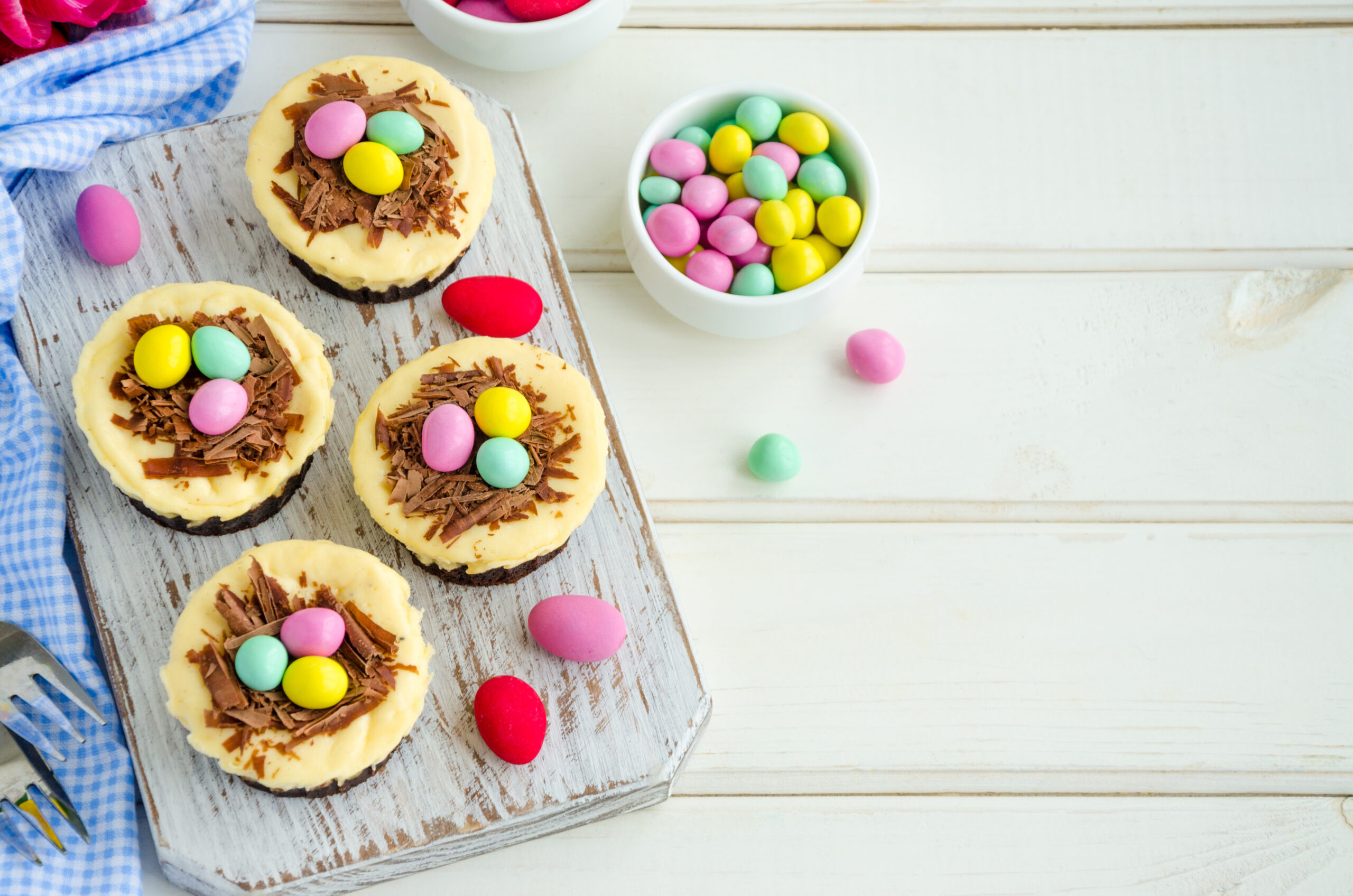 Easter Brownie Cheesecake Birds Nests; brownie crust, creamy cheesecake filling topped with mini eggs for a delicious Easter dessert recipe! Easter mini brownie cheesecake Bird's Nest with chocolate and candy eggs. Easter dessert. Funny food idea for children.
