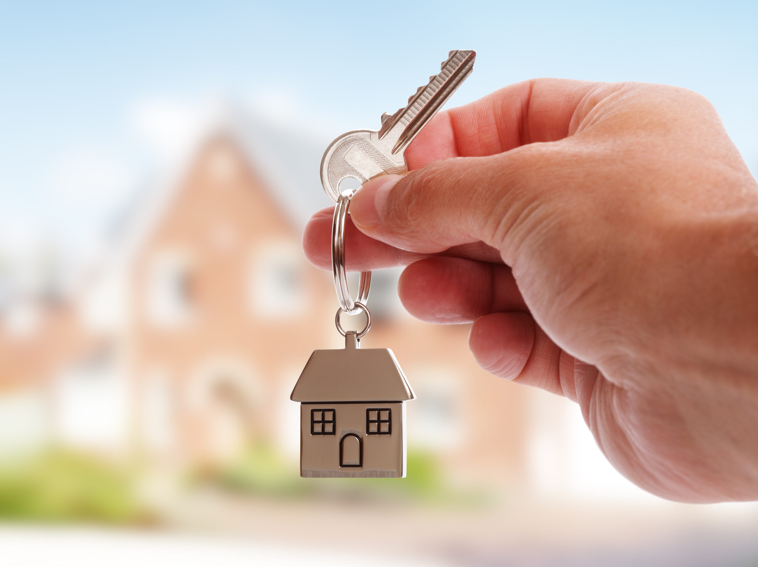 What do people look for in a new home? - Holding house keys on house shaped keychain in front of a new home