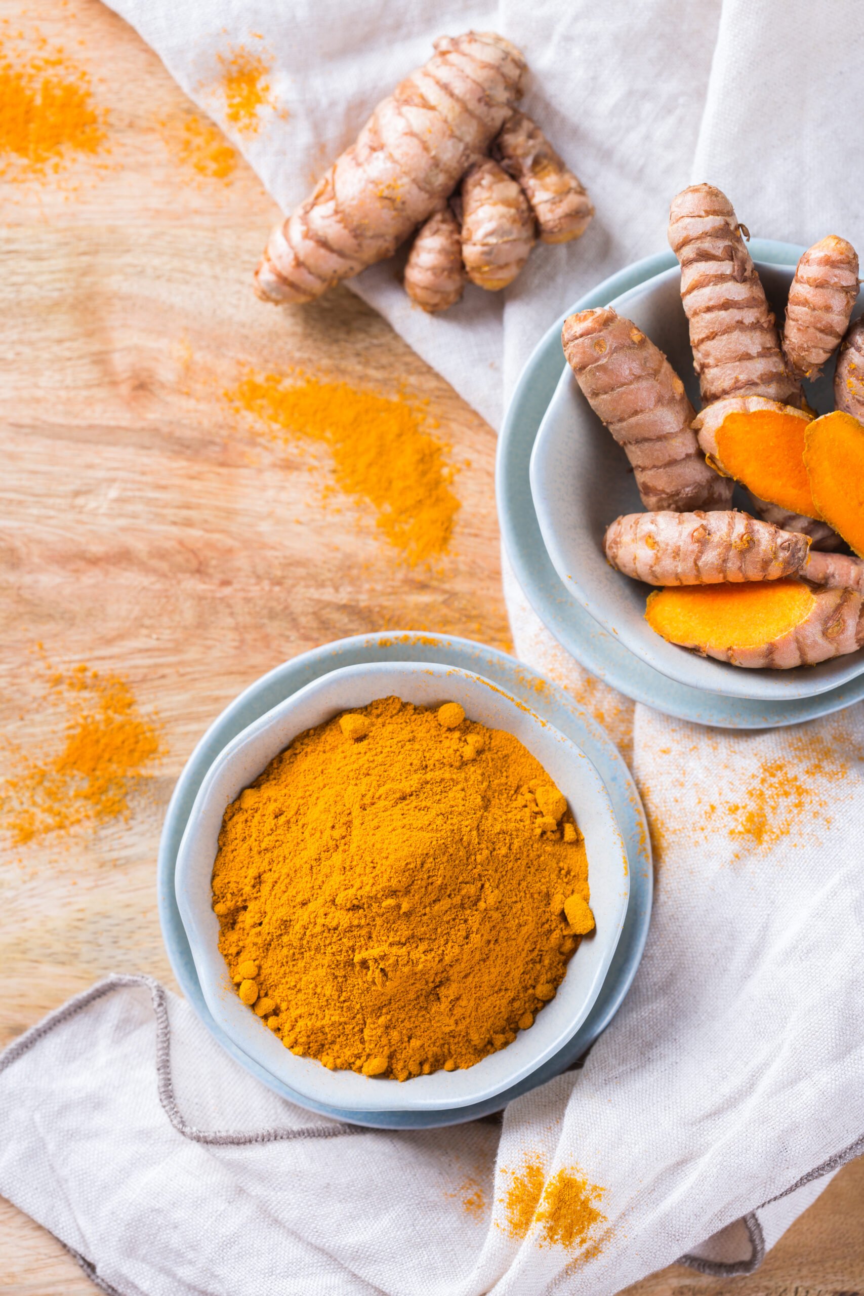 Benefits of Turmeric; Food and drink, diet nutrition, health care concept. Raw organic orange turmeric root and powder, curcuma longa on a cooking table. Indian oriental low cholesterol spices.