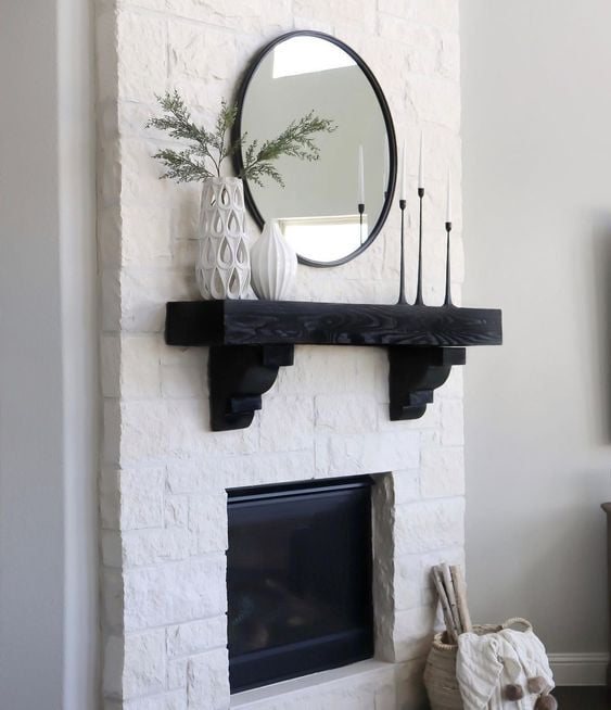 This captivating photo showcases a minimalist black round mirror that has been hung above a stunning mantel. The black mirror creates a striking contrast against the white fireplace and neutral decor of the room, drawing attention to the unique yet simple design. Its placement above the mantel adds depth and reflection to the space, creating an eye-catching and elegant display.