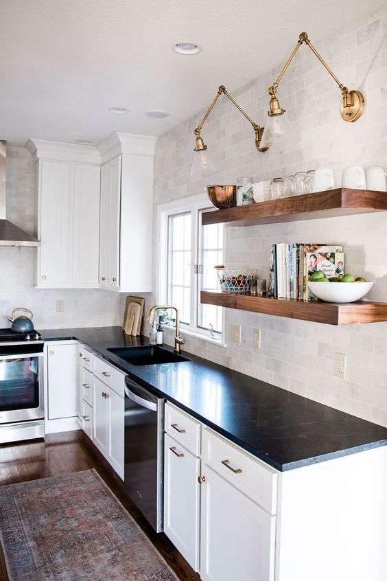 This classic black and white kitchen combines timeless design elements with trendy accents to create a stylish and modern space. The use of gold and brass hardware adds a touch of warmth and luxury, elevating the overall aesthetic of the kitchen. Open shelving and marble tile backsplash
