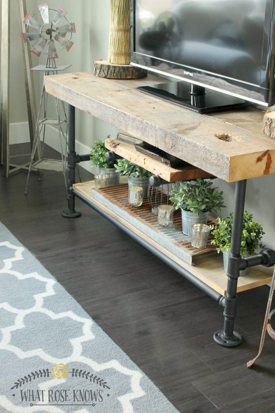 farmhouse TV stand ideas; An industrial farmhouse TV unit that seamlessly combines rugged black pipes and reclaimed wood for a distinctive and stylish look. The sturdy black pipes not only provide excellent support for the unit, but also add an industrial touch to the overall design. The reclaimed wood shelves add a warm and rustic element, highlighting the natural beauty of the wood grain. With its perfect marriage of industrial and farmhouse aesthetics, this TV unit is sure to be a focal point in any modern living room.