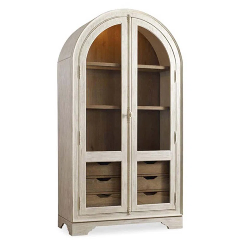 Rosalind Wheeler French Solid Wood China Cabinet is a versatile and stylish addition to your home. This charming piece is a fusion of Mediterranean and American pastoral styles, exuding warmth and elegance. Perfectly suited for small apartments and compact living spaces, this multi-storey cabinet functions as a dining side cabinet, bookcase, and display cabinet. Crafted from solid wood and boasting intricate arch details!