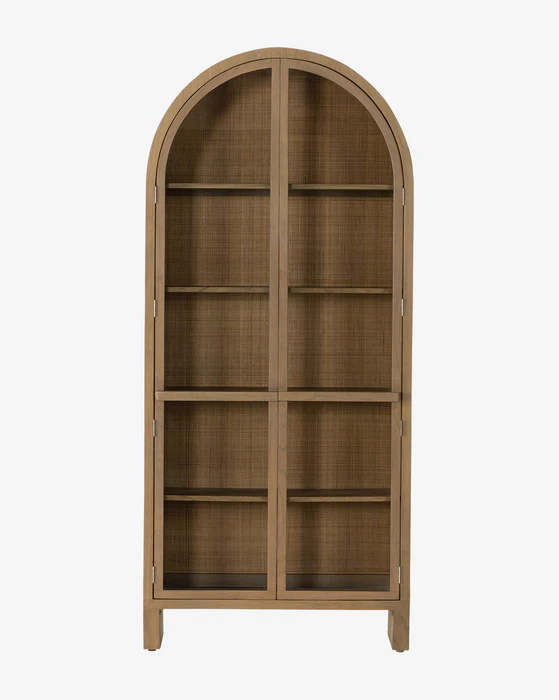 Badgley Cabinet by McGee & Co. is an artistic fusion of functionality and style. Made from solid mindi wood, it features a burnished finish exuding a smooth, shiny allure. Its standout feature is the glass-front cabinetry, revealing the woven, natural cane backing inside. With permanently fixed shelves for systematic display and an intriguing arch shape reaching all the way to the floor, the Badgley Arched Cabinet is an extraordinary addition to your dining or living spaces.