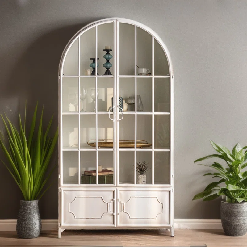 This arched cabinet found on Wayfair is not just furniture, it is a statement piece that can double as home decor. Manufactured using toughened glass for the cabinet door, it is strong and serves as an ideal display area for home furnishings or collections. The overall frame, made of iron, ensures sturdiness without adding unnecessary weight. This cabinet offers extensive storage space, helping reduce clutter and maximize utilization. Designed with intentional distressing, the paint is purposely rubbed off to create a uniquely distressed look.