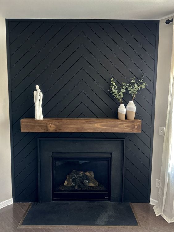 15 Black Shiplap Fireplace Ideas for a Moody Vibe; A stylish black herringbone shiplap fireplace adding a modern and elegant touch to the room.