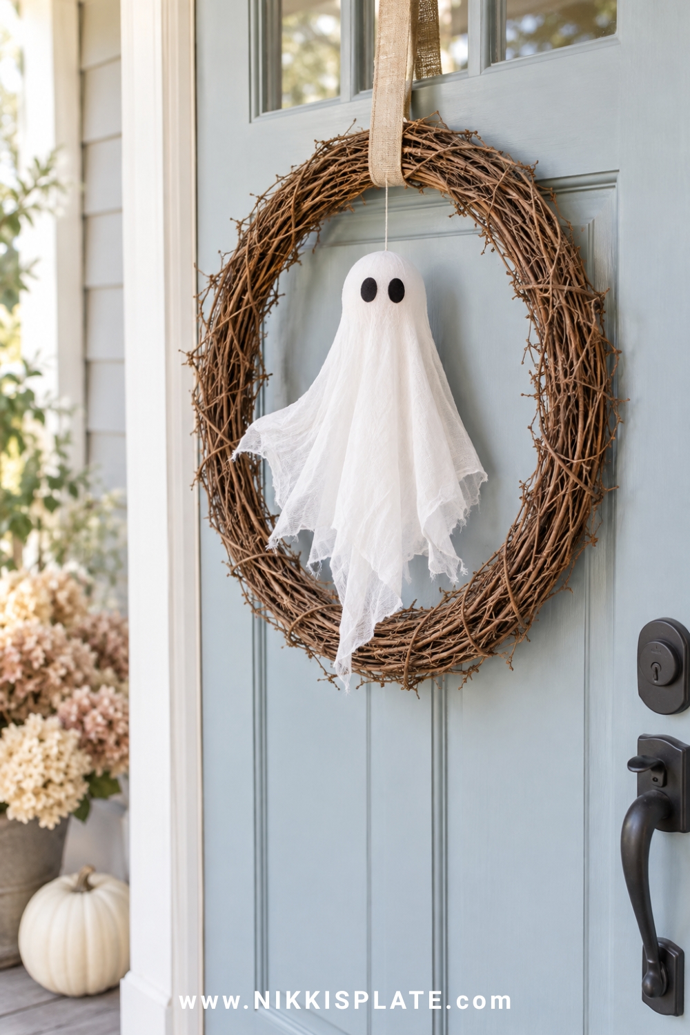 White fabric ghost floating inside a simple grapevine Halloween wreath