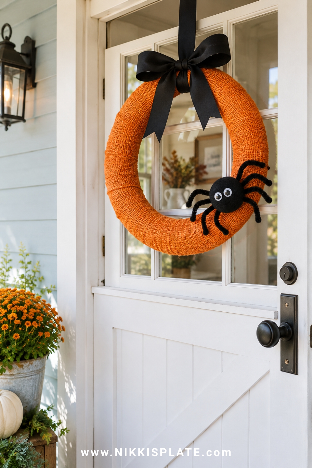 Orange wrapped Halloween wreath with a black bow and friendly craft spider