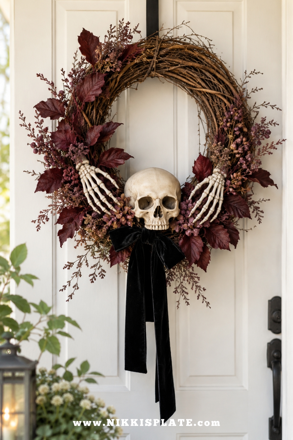 Grapevine Halloween wreath decorated with two skeleton hands, an ivory skull and burgundy foliage