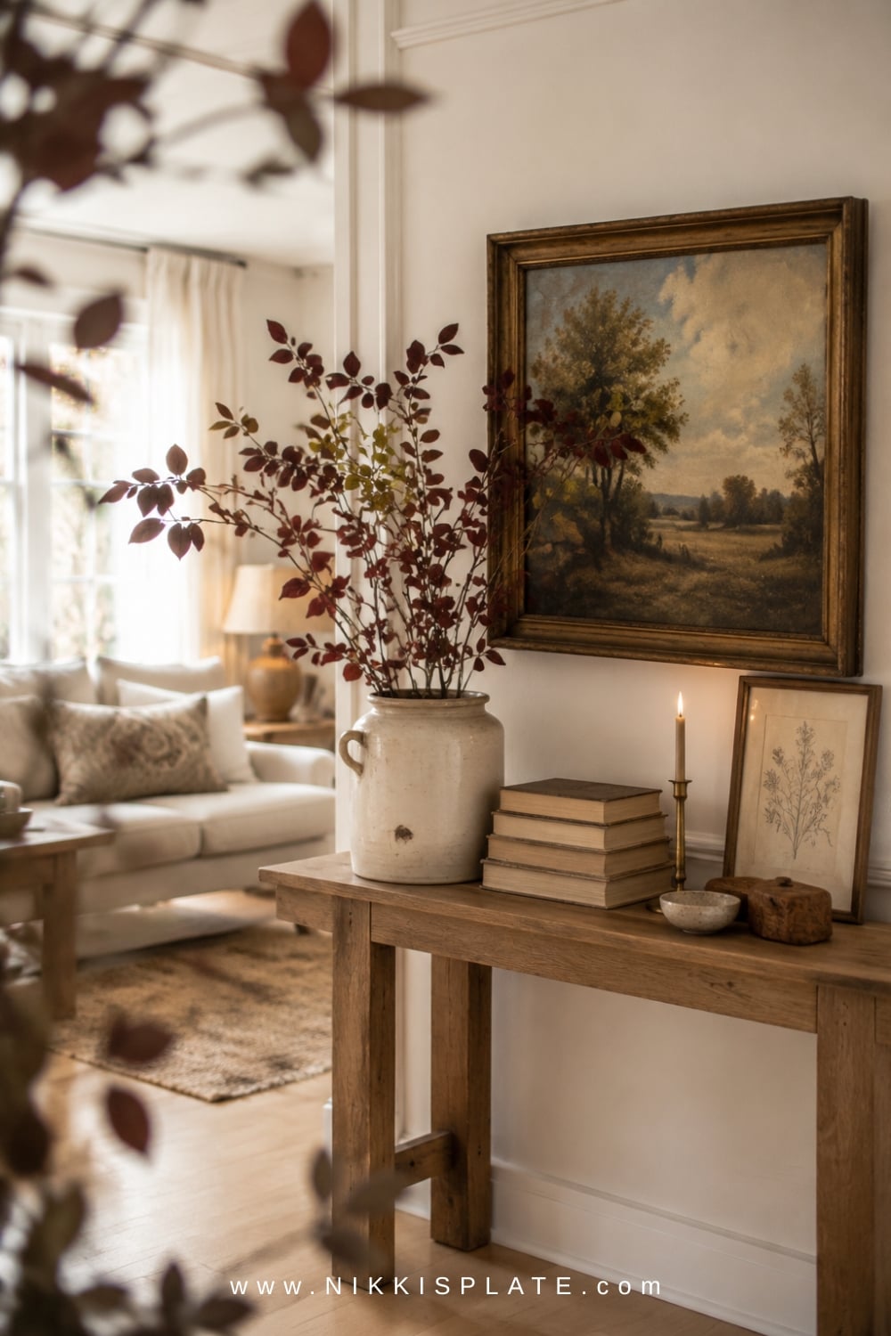 decor.webpCollected fall entryway with vintage landscape art, stacked books, pottery, and natural accents