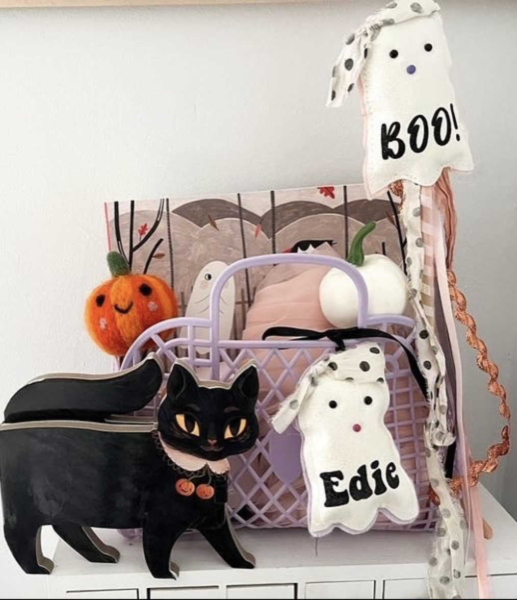 Lavender Halloween pet boo basket with ghost plush labeled "Edie," felted pumpkin toy, mini white pumpkin, and a black cat decoration