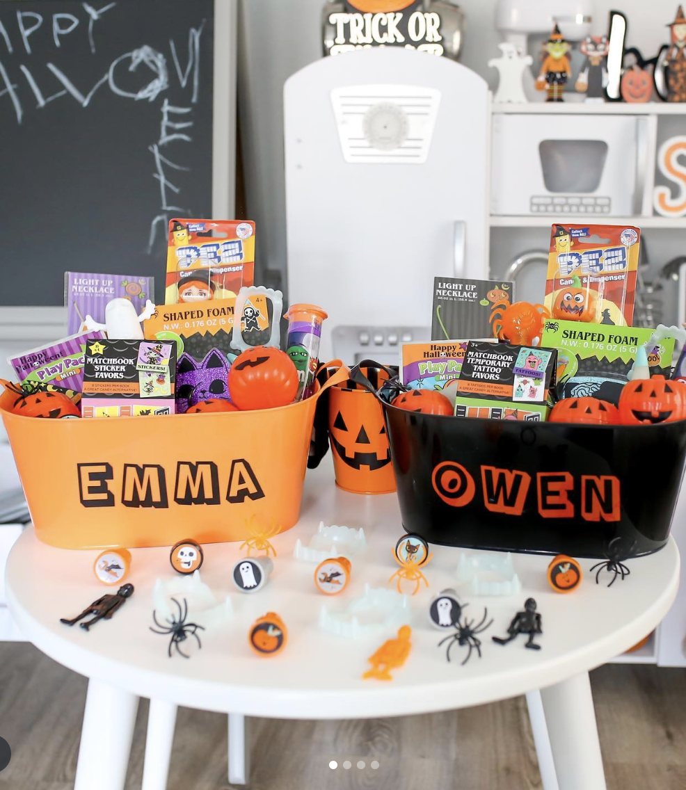 Classic Halloween boo baskets for kids labeled Emma and Owen, filled with toys, stickers, tattoos, and Halloween-themed treats in orange and black bins.