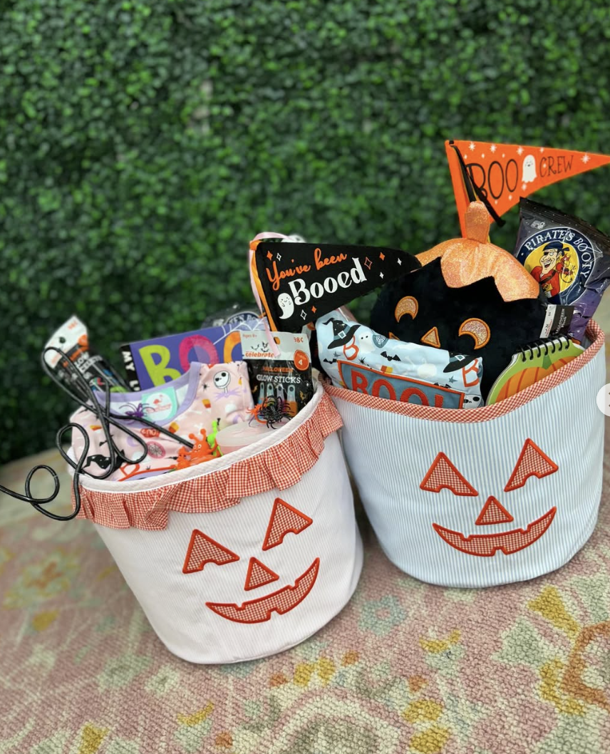Halloween boo baskets for kids in pumpkin-themed fabric bins, filled with glow sticks, toys, books, and “You’ve Been Booed” signs.