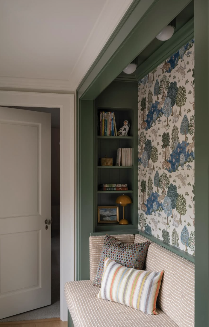 Built-in reading nook with green trim, animal wallpaper, and striped cushions