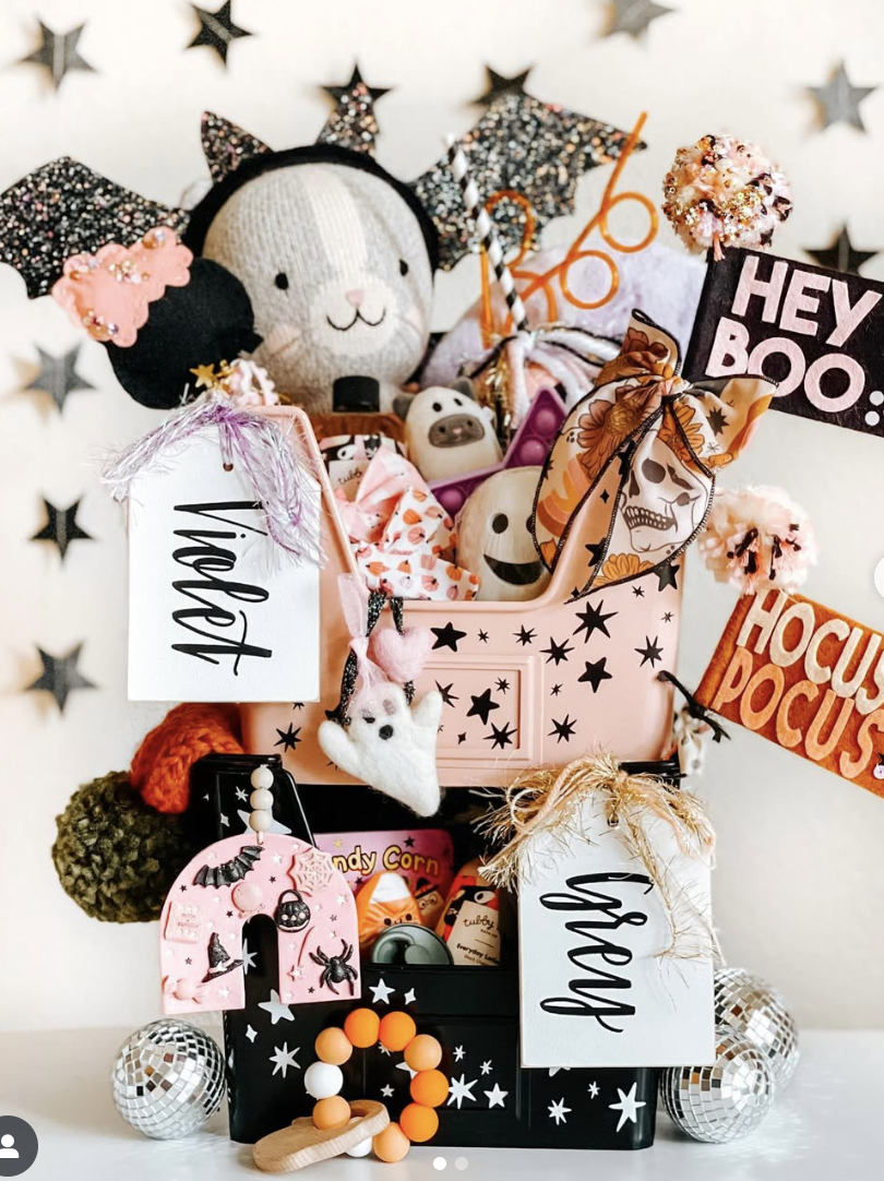 Custom Halloween boo baskets for kids labeled Violet and Grey, filled with themed toys, ghost decorations, candy, and festive accessories.