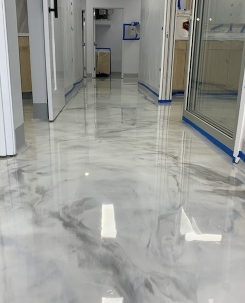High-gloss metallic epoxy resin floor with gray and white swirls in a modern hallway under construction.