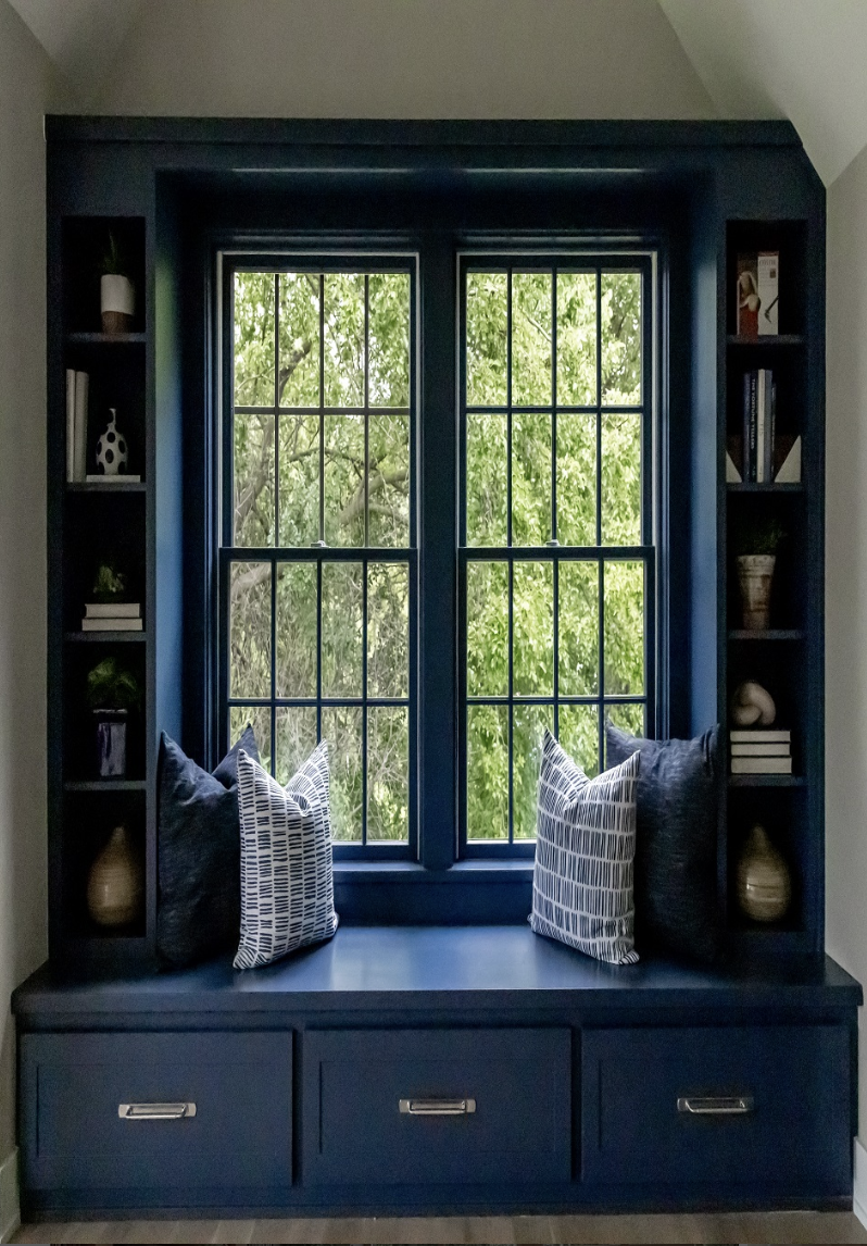 Built-in navy reading nook with window seat, drawers, and minimal shelves