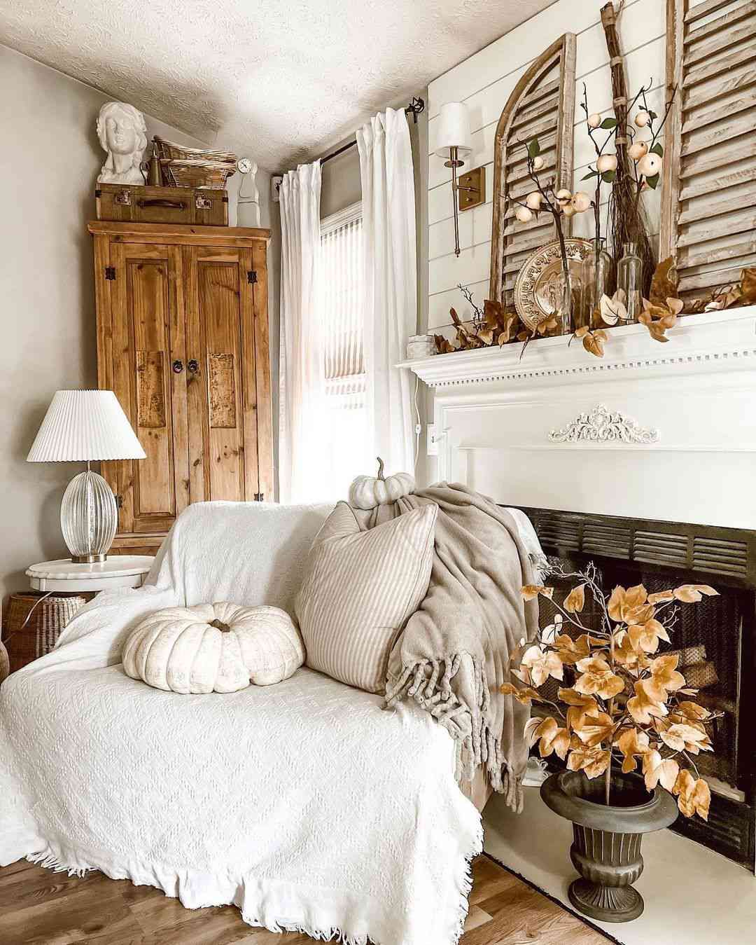 Neutral farmhouse living room with pumpkins, throw pillows, fall mantel decor, and soft autumn accents
