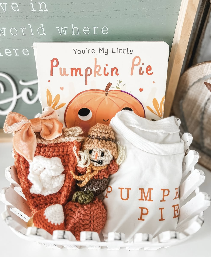 Fall-themed boo basket for baby featuring a “Pumpkin Pie” book, matching onesie, and handmade crochet toys in a white basket.