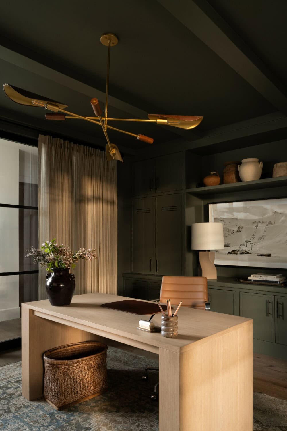 Studio McGee office design featuring dark green built-in cabinetry, a modern light fixture, and a minimalist wood desk.