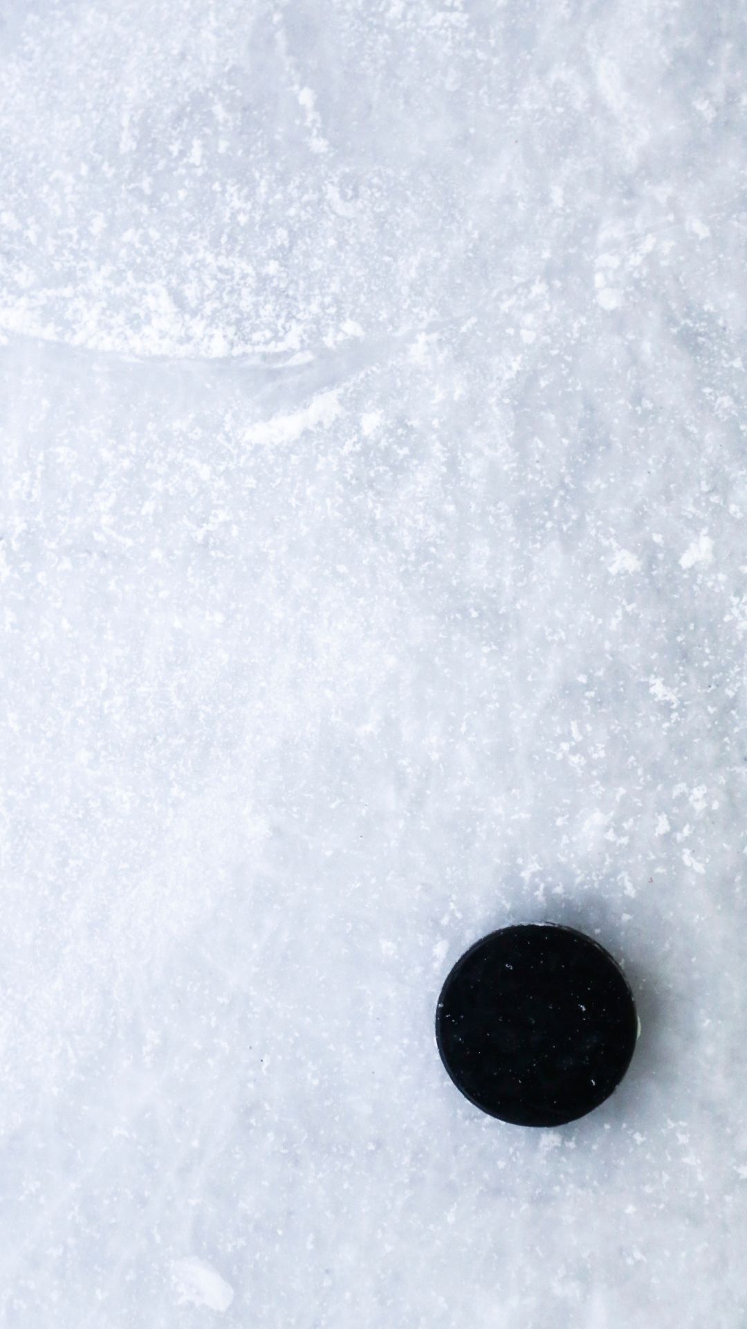 Minimalist winter wallpaper with black hockey puck on frozen white ice surface