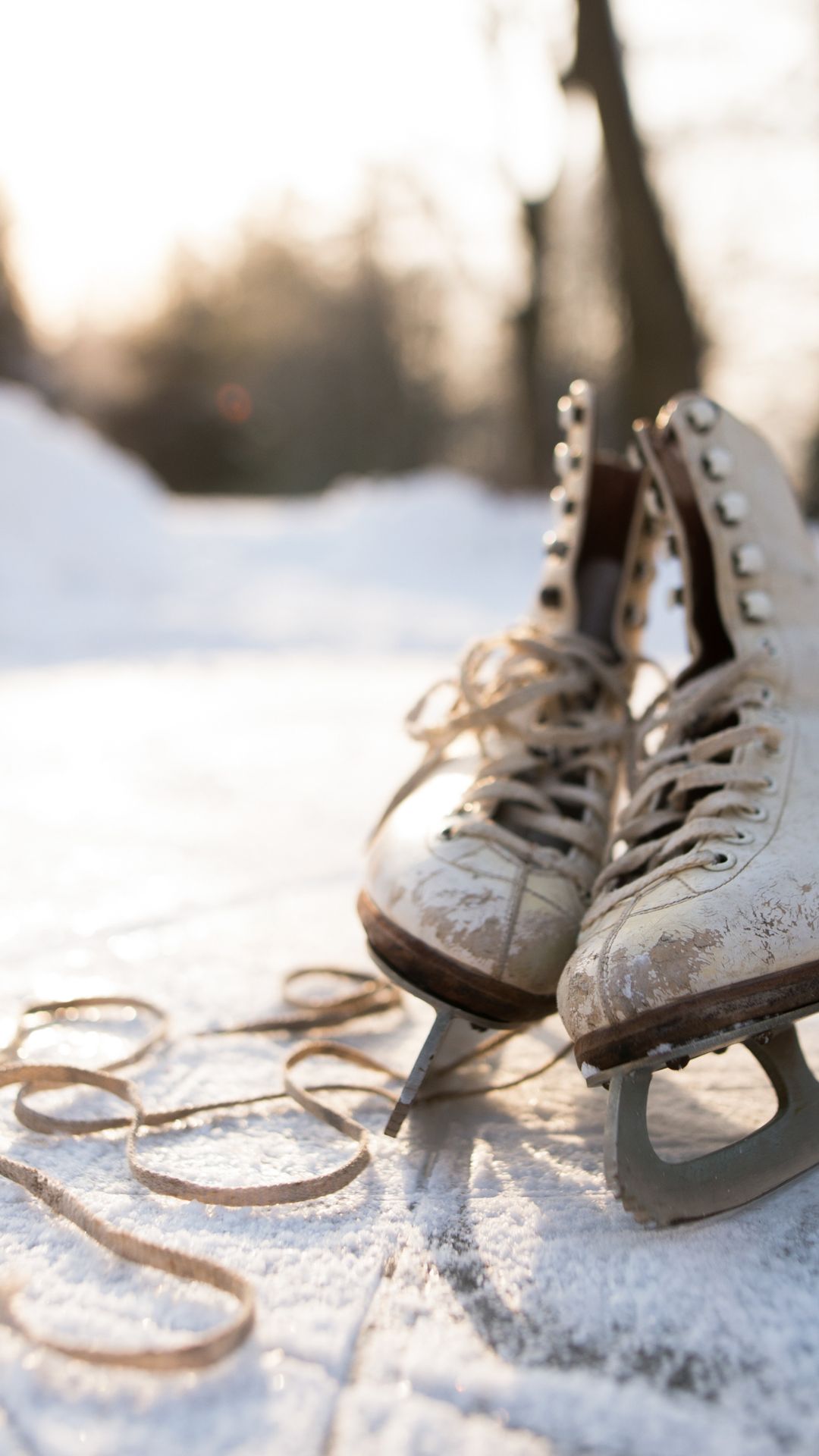 Minimalist winter wallpaper with vintage ice skates on outdoor frozen pond