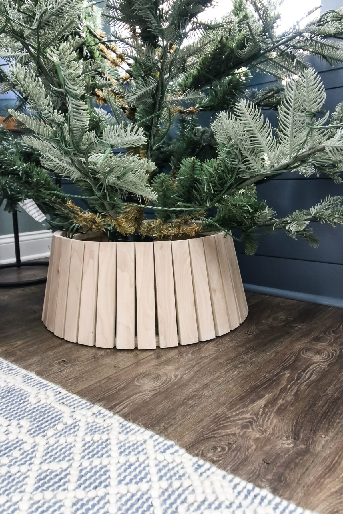 Christmas tree with a minimalist wood slat tree collar in natural finish for a simple modern holiday decor style.