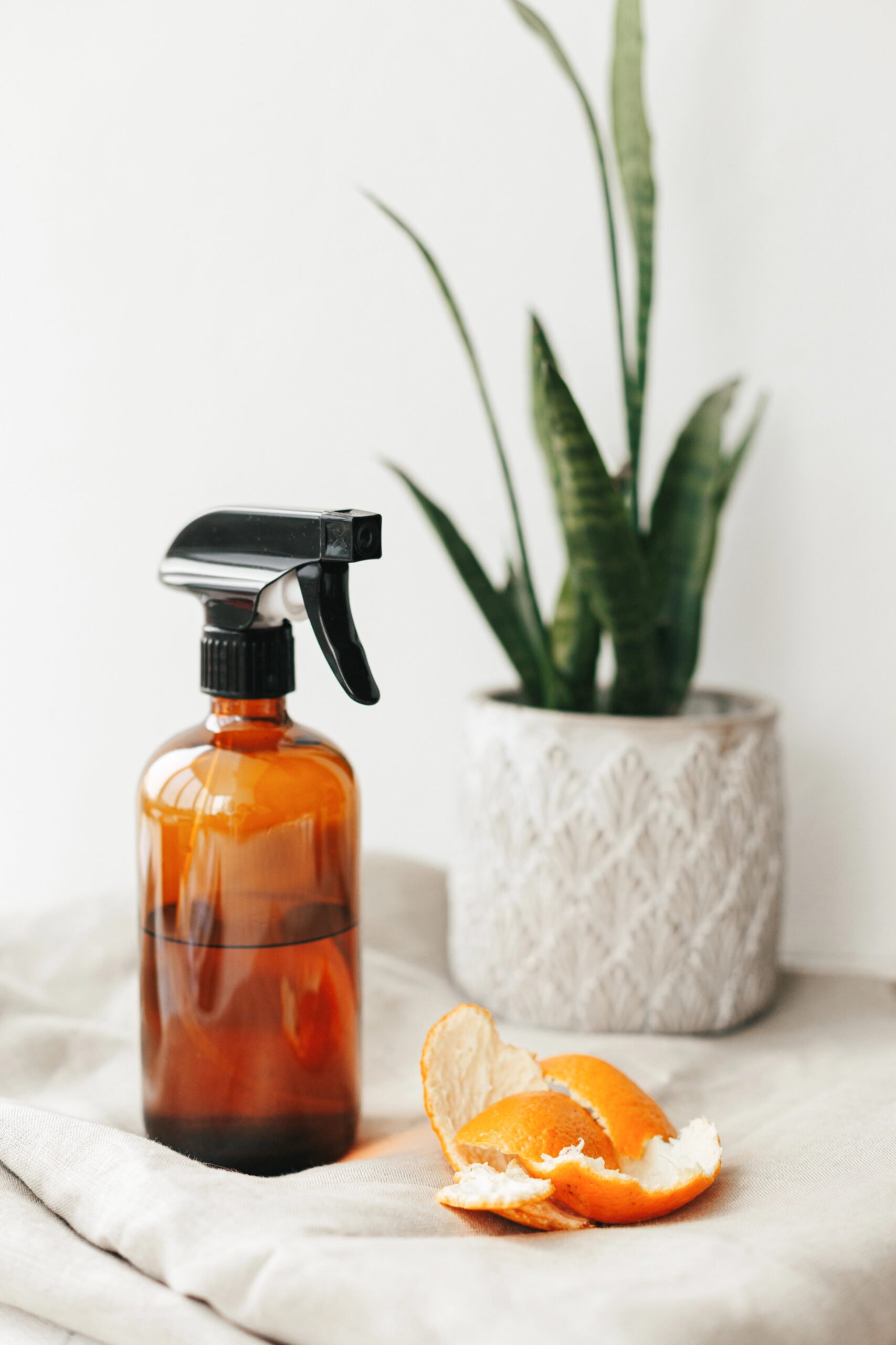 Amber glass spray bottle with natural all-purpose cleaner and orange peel - a simple and eco-friendly homemade homemaker gift idea for Christmas.