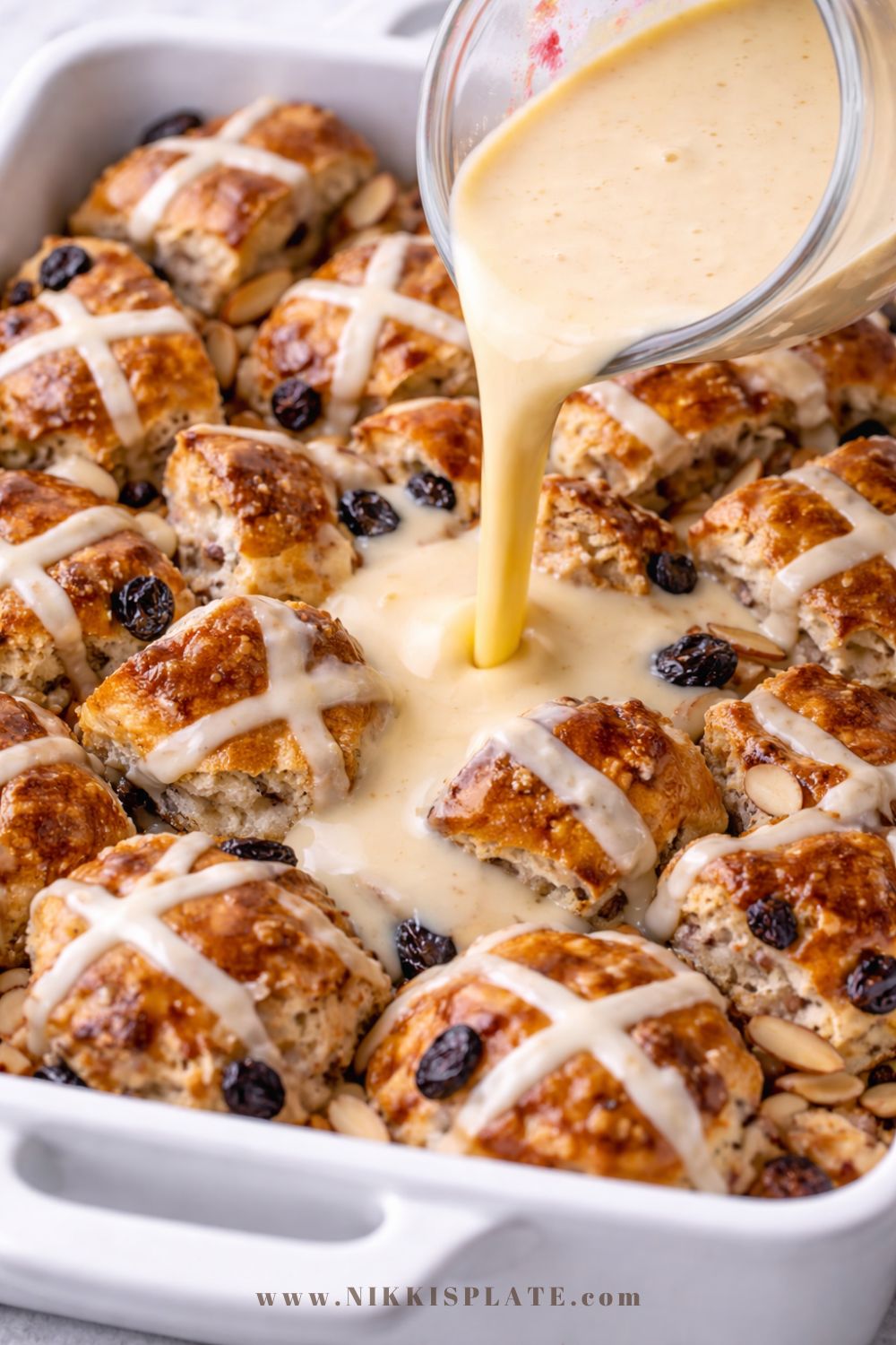 Pouring vanilla custard over hot cross buns for French toast casserole